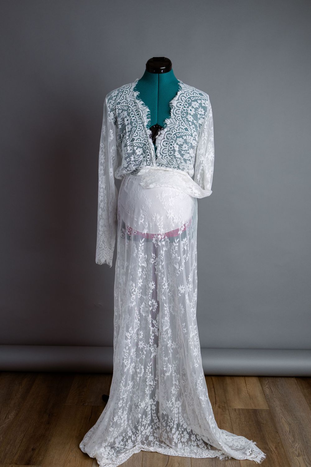 White lace maternity dress displayed on green mannequin.
