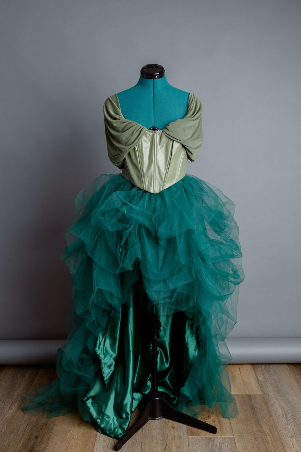 A green corset and skirt with dramatic tulle layers displayed on a mannequin.