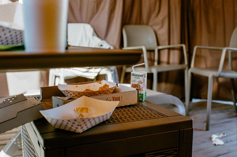 A takeout burger and fries served in paper wrappers on a wooden table at a casual dining restaurant.