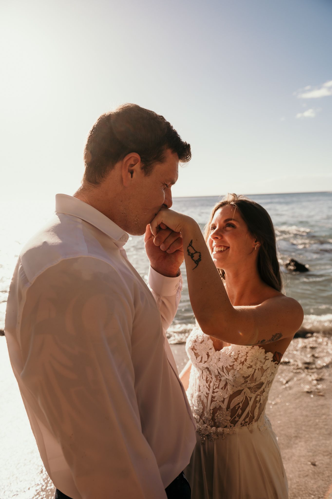 Romantic beachside wedding moment captured during golden hour with waves crashing in background.