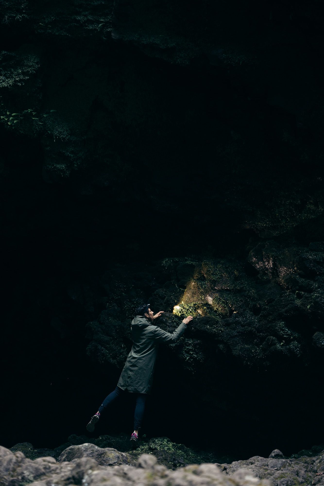 Randonneuse avec une lampe frontale qui regarde la paroi d'une cascade au levada do caldeirao verde à Madère