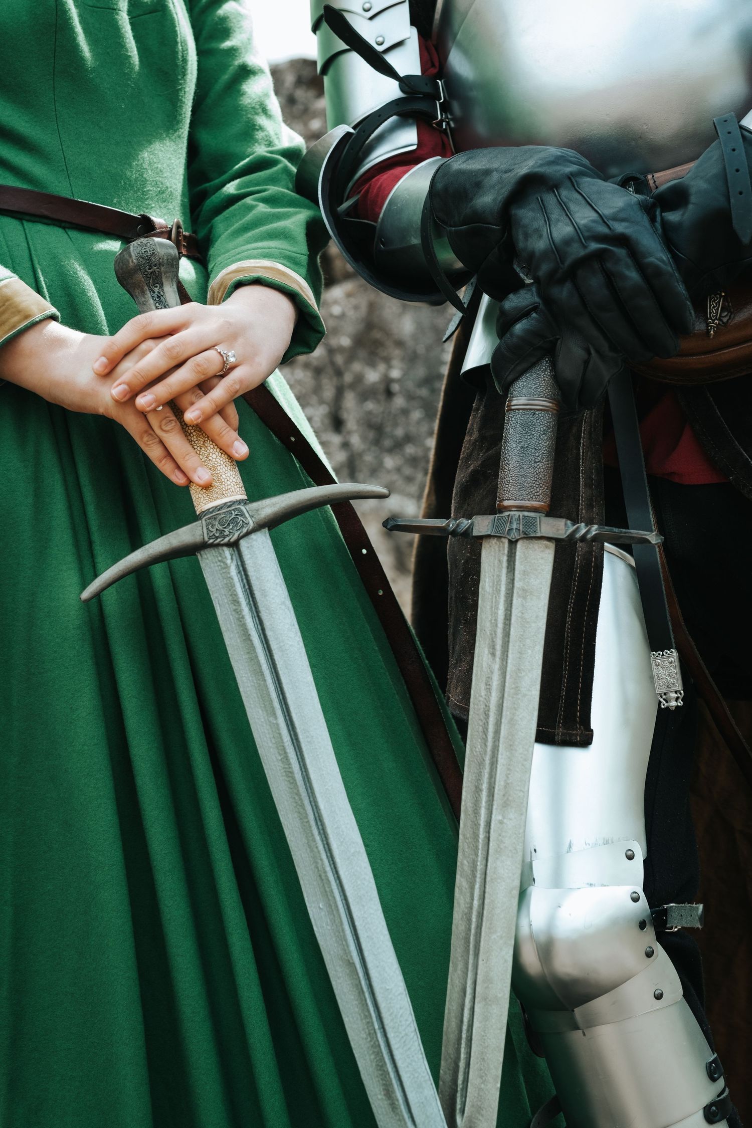Medieval sword with ornate handle details rests against green fabric.