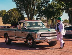 Vintage Chevrolet C10 pickup truck parked while someone in white clothing stands beside it.