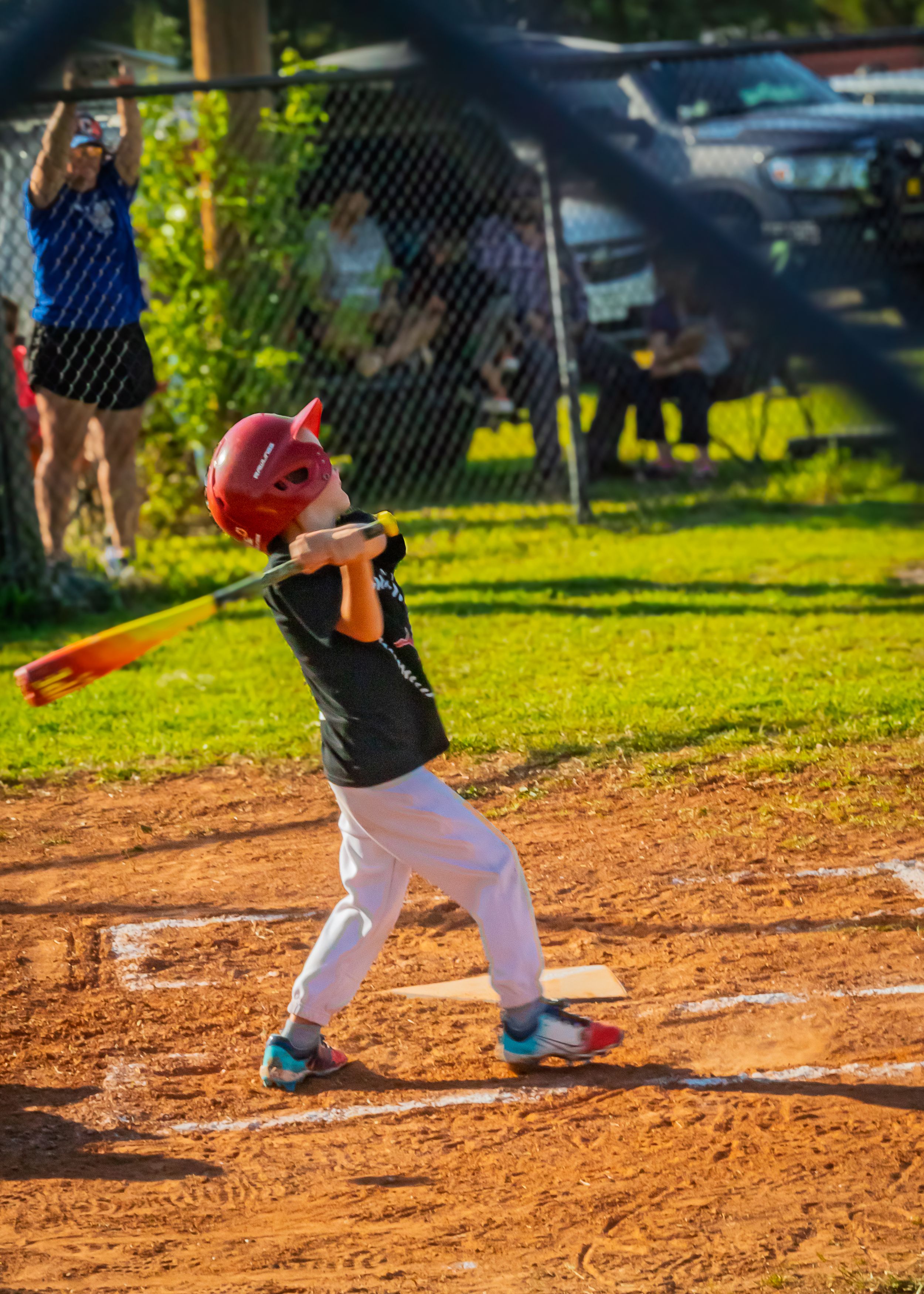 Young baseball player in black and white uniform takes a batting stance on dusty field during game practice.