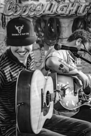 Black and white image of musicians performing with acoustic guitars at a Coors Light branded event.