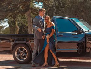 Elegant couple in formal attire standing together next to a black vehicle.