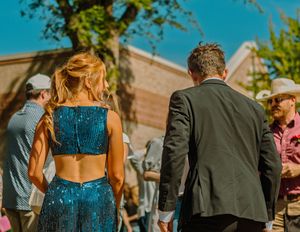 People at an outdoor event with someone wearing a sparkly blue two-piece outfit walking through the crowd.