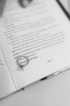 A black and white close-up photograph of an open book page with text and an engagement ring resting on it.