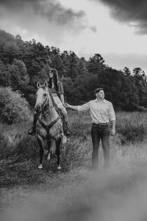 Black and white photo of two people with a white horse in a mountainous countryside setting.