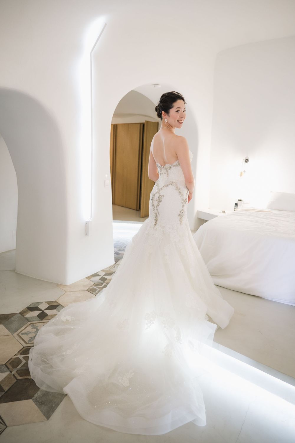 Stunning mermaid wedding gown with intricate lace details and flowing train showcased in a bright white interior.