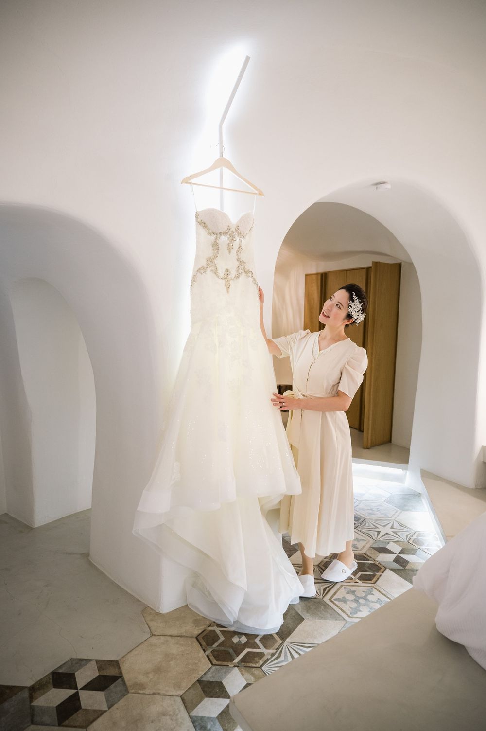 White wedding gown displayed in sunlit Mediterranean villa interior with geometric floor tiles.
