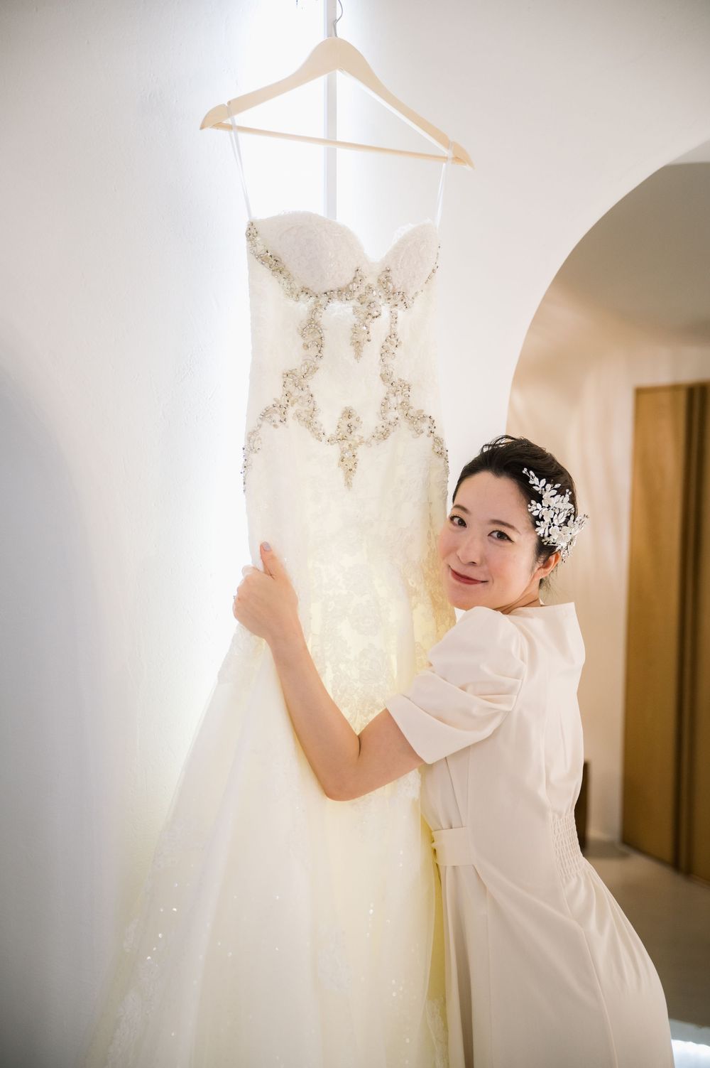 Beautiful embellished wedding gown hanging in bright Mediterranean villa with arched doorways.