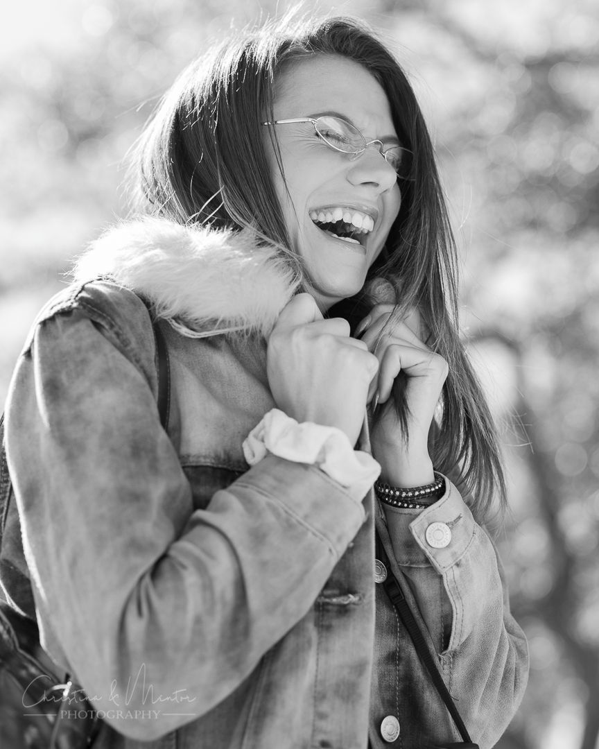 Black and white candid photo showing joyful laughter while wearing a denim jacket.
