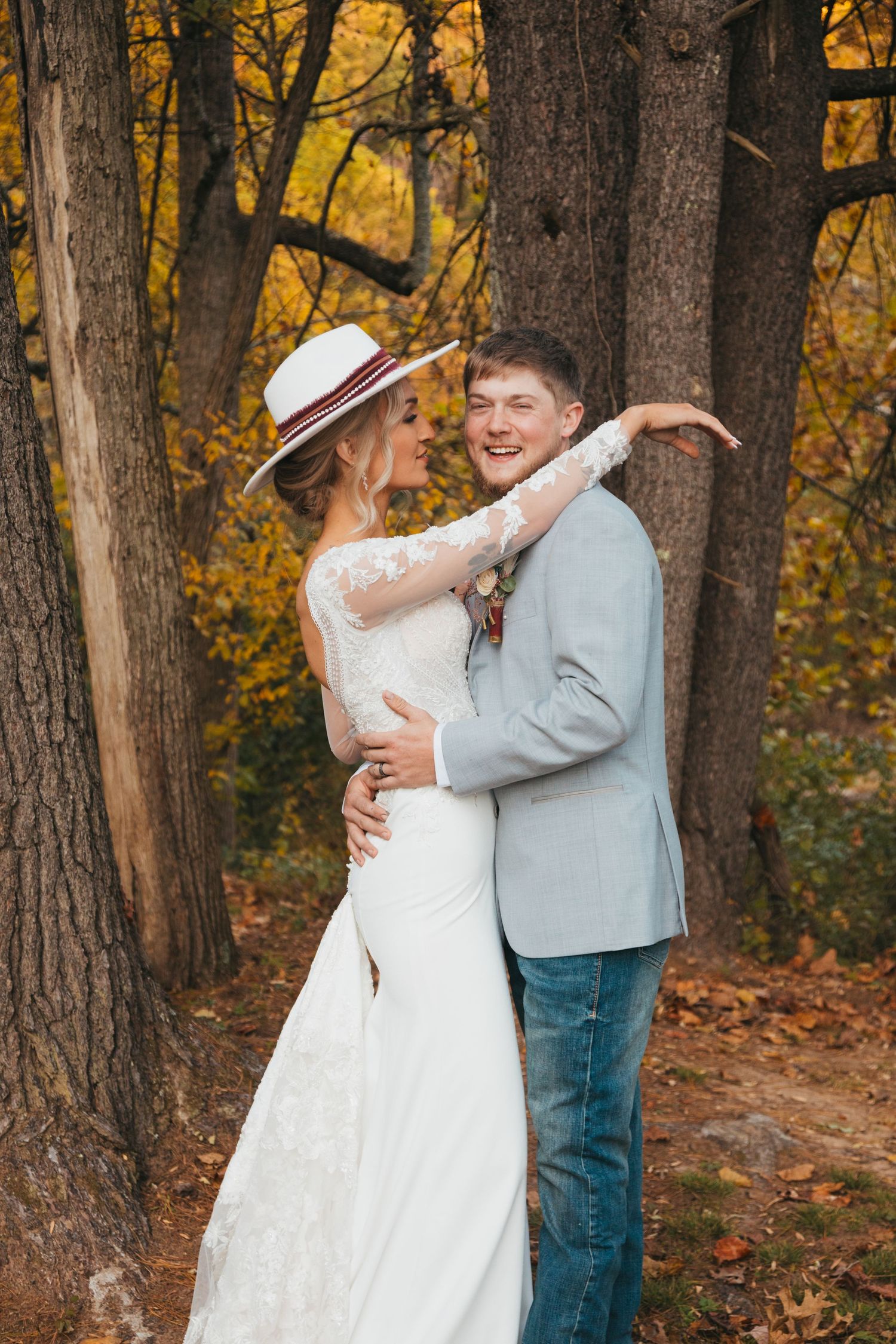 Playful wedding couple portraits in a wooded setting with autumn colors.