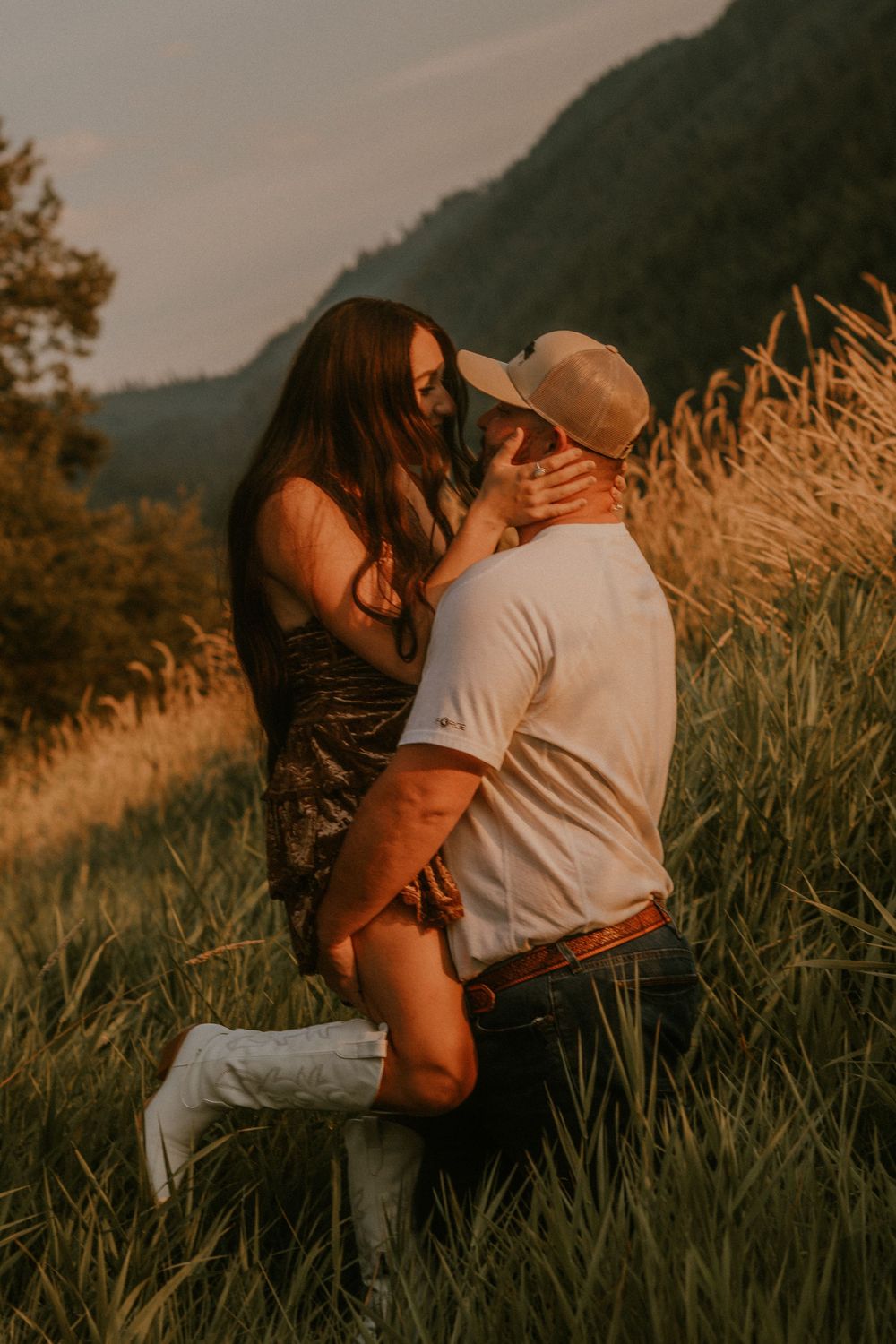 Two people in warm clothing embrace intimately in a monochrome outdoor setting with mountains in the background.