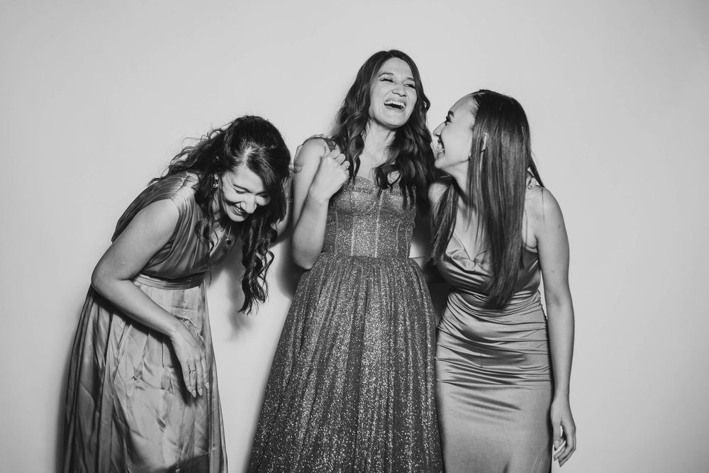 Dos amigas posando y divirtiéndose en el estudio de fotografía móvil sobre un fondo blanco.