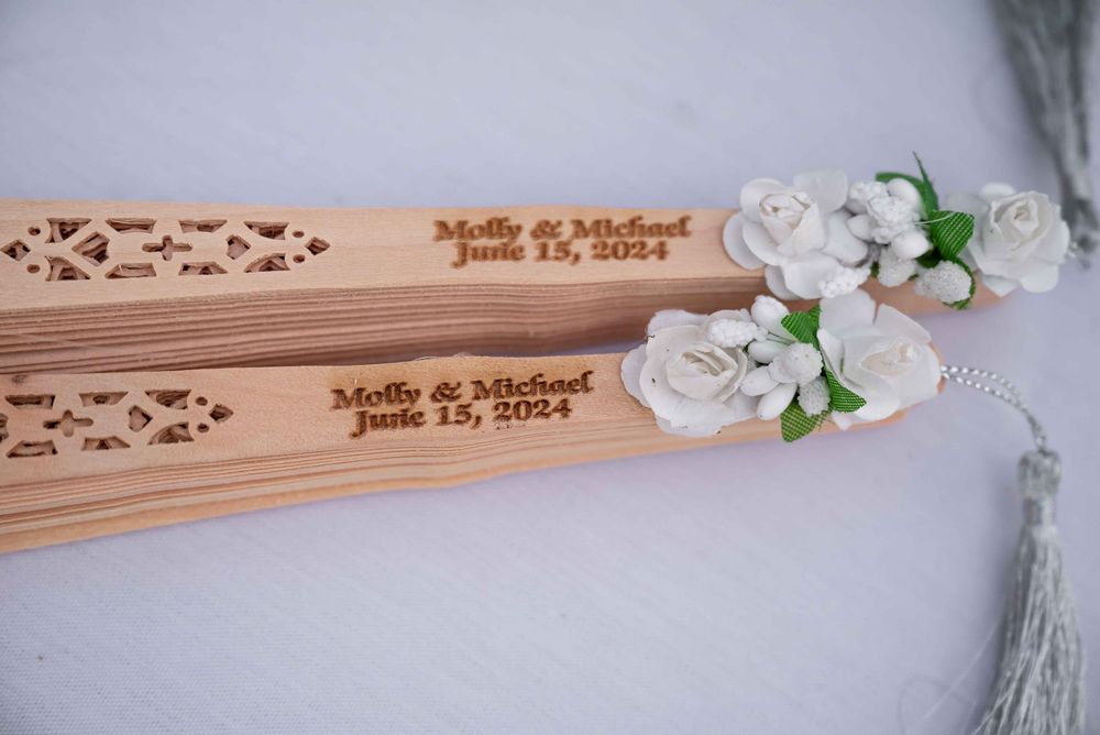 Decorative wooden wedding fan favors with engraved names and date.