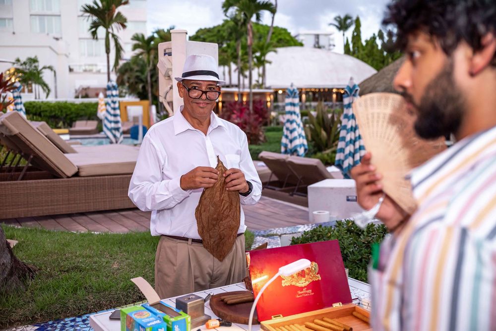Outdoor tropical resort event with vendor serving refreshments near palm trees and lounge chairs.