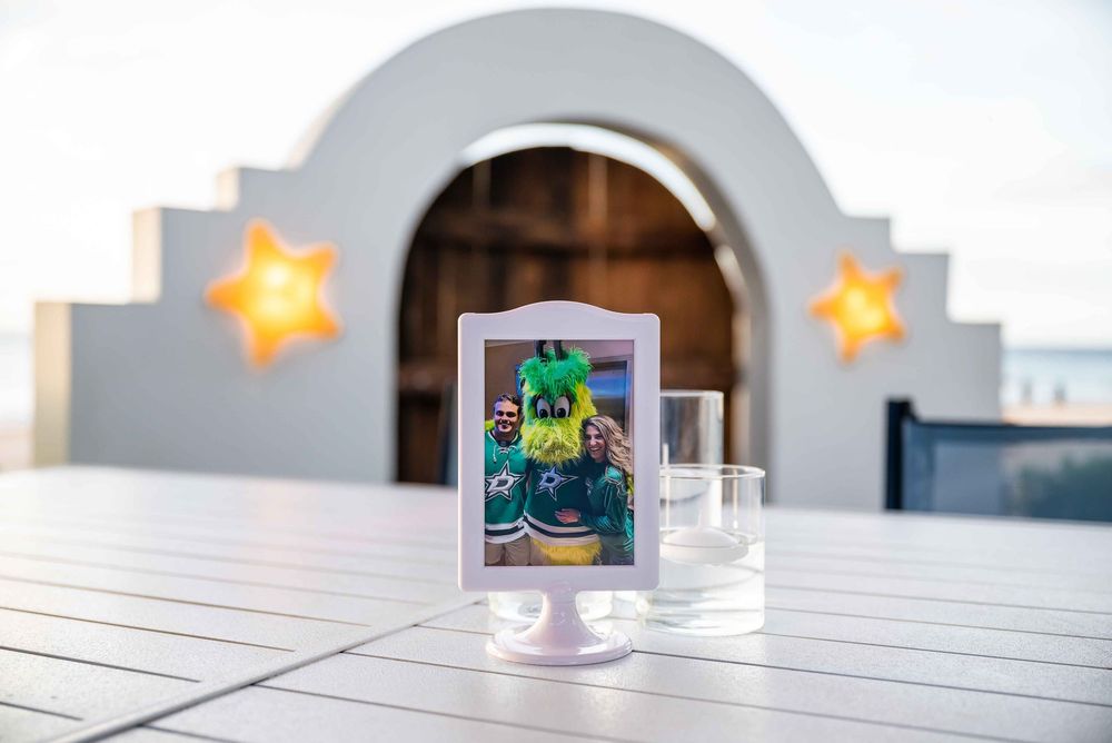 A small framed photo stands on a wooden table with decorative star ornaments in the background.