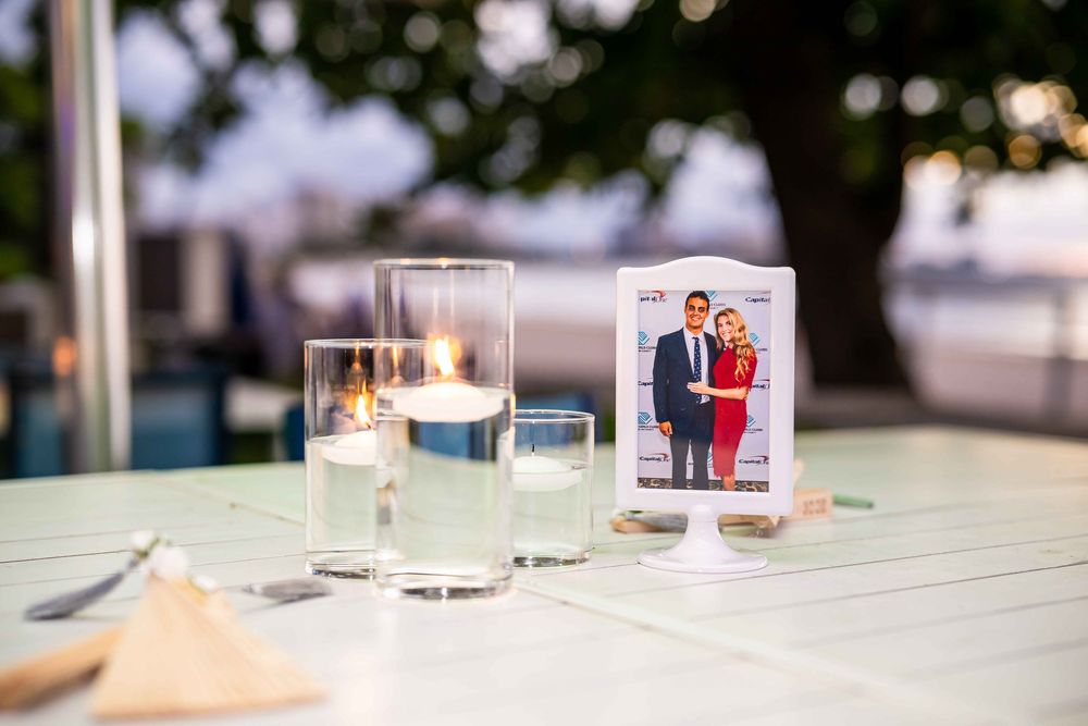 Table setting with candles and framed photograph at outdoor event.