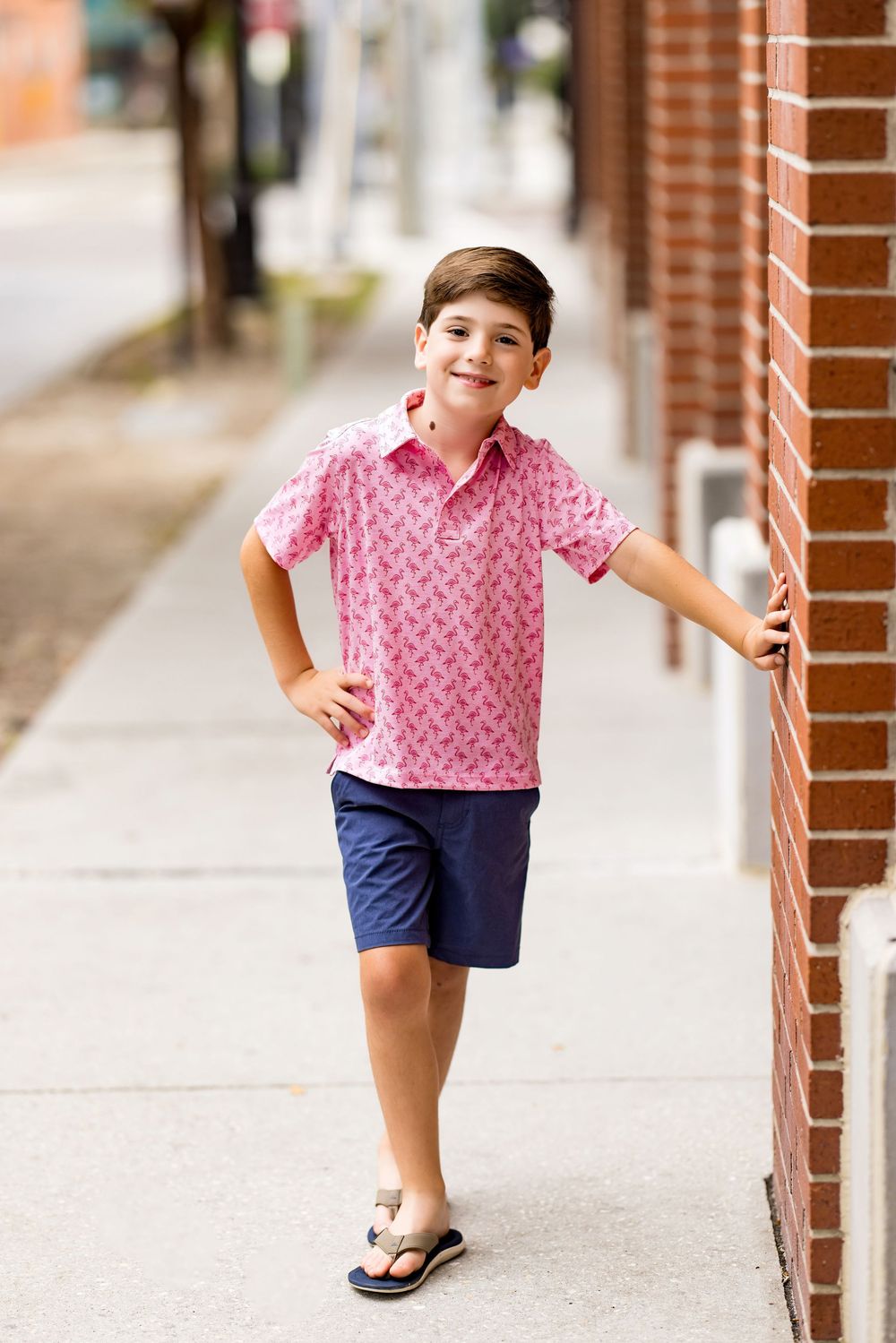 Dynamic series of poses in pink shirt and navy shorts against urban backdrop.