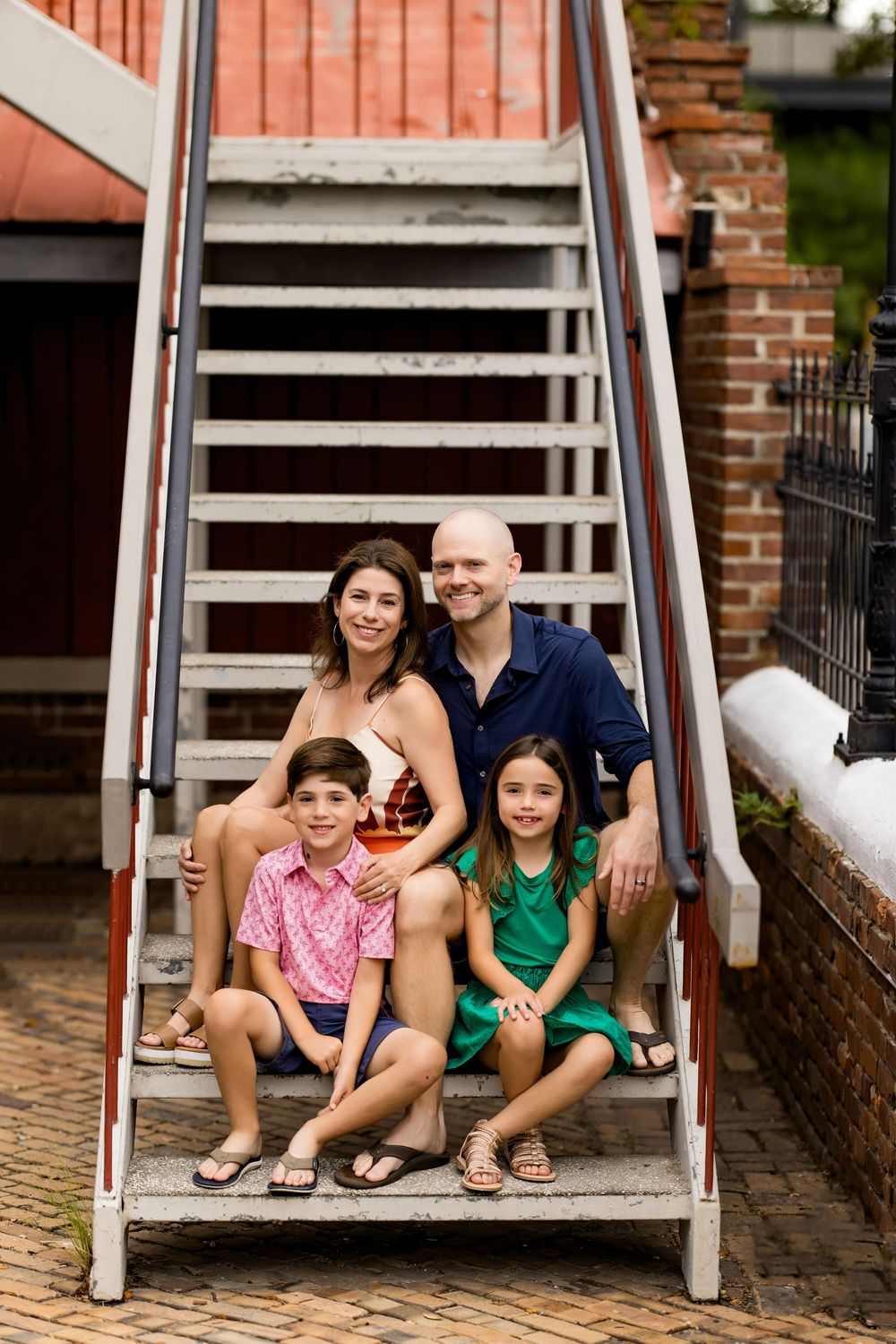 Family sitting together on an outdoor staircase during a casual summer photoshoot.
