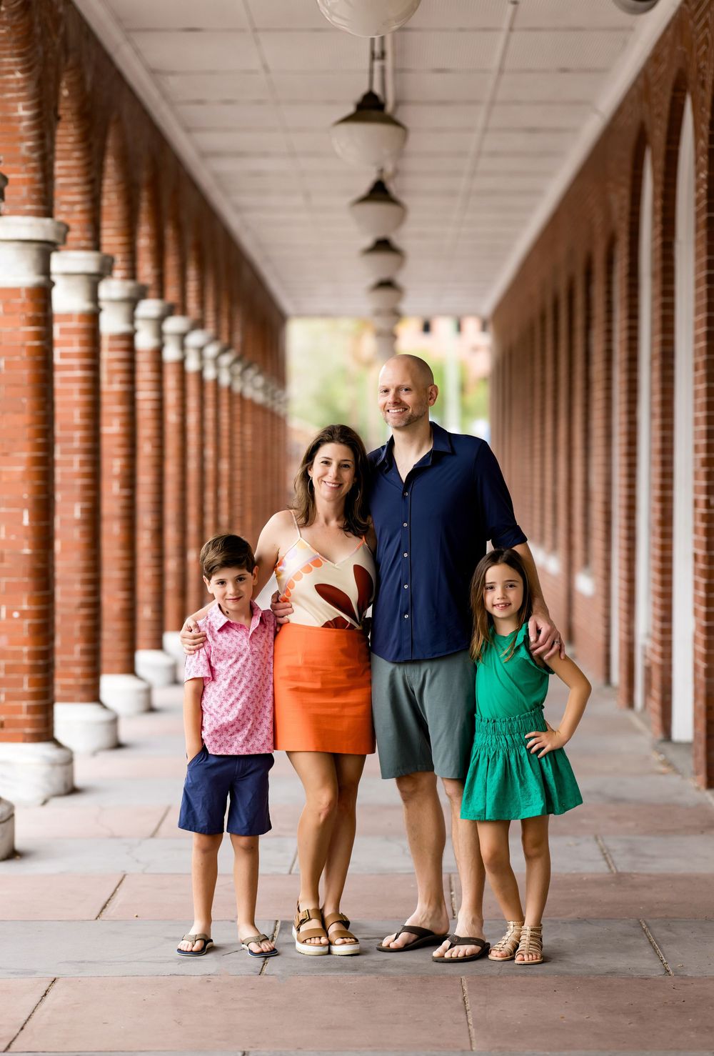 Family standing together under a covered brick colonnade walkway.