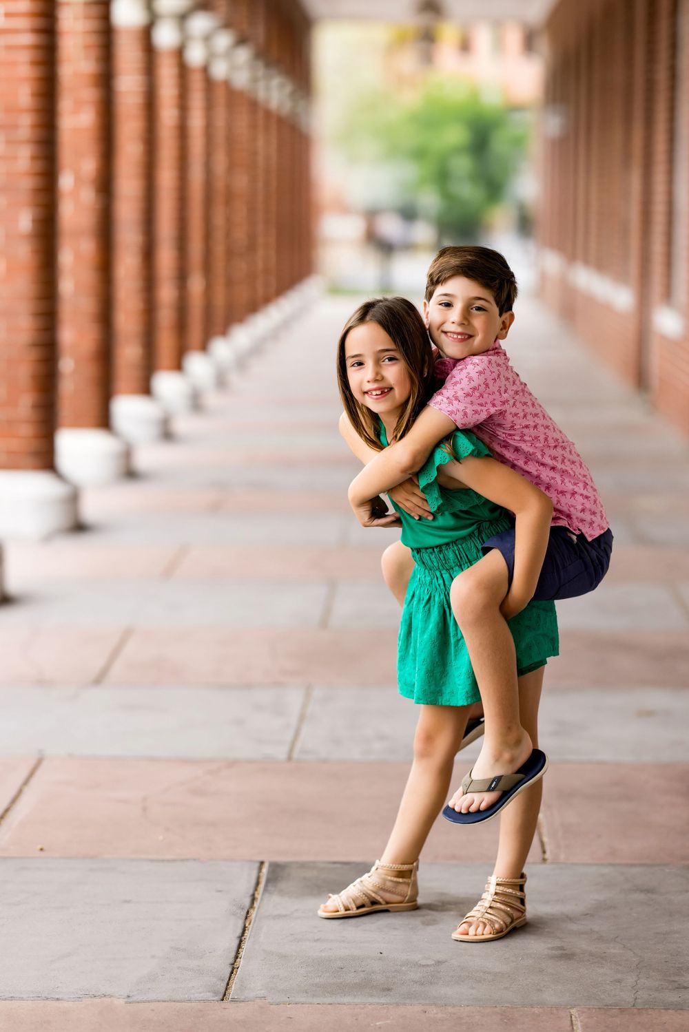 Playful children posing and laughing in a covered walkway with brick columns. DigitalMyst Photography