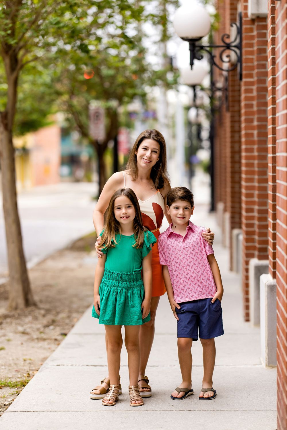 Children walking together on sidewalk wearing coordinated green and pink summer outfits.
