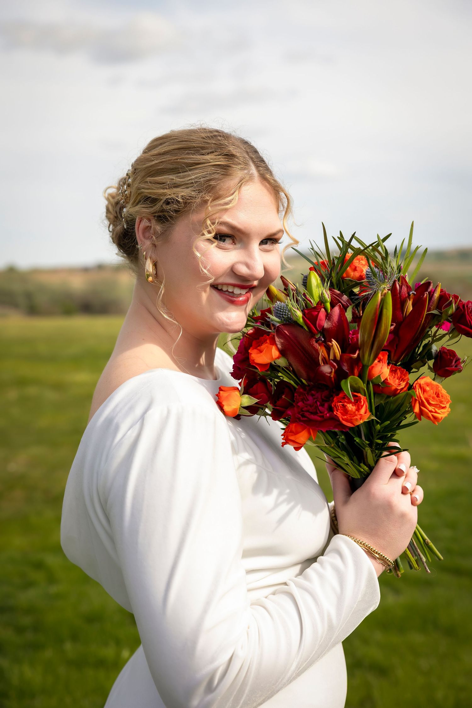 Bride headshot with red, orange, purple, and green bouquet. The Vanity Beauty, Boise wedding hair stylist. Boise wedding makeup artist.