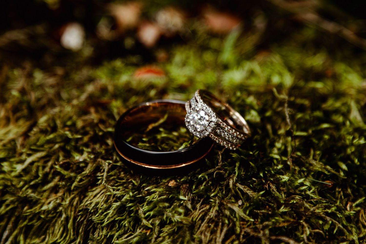 Close-up of hands exchanging wedding rings during outdoor ceremony with officiant holding brown leather book.
