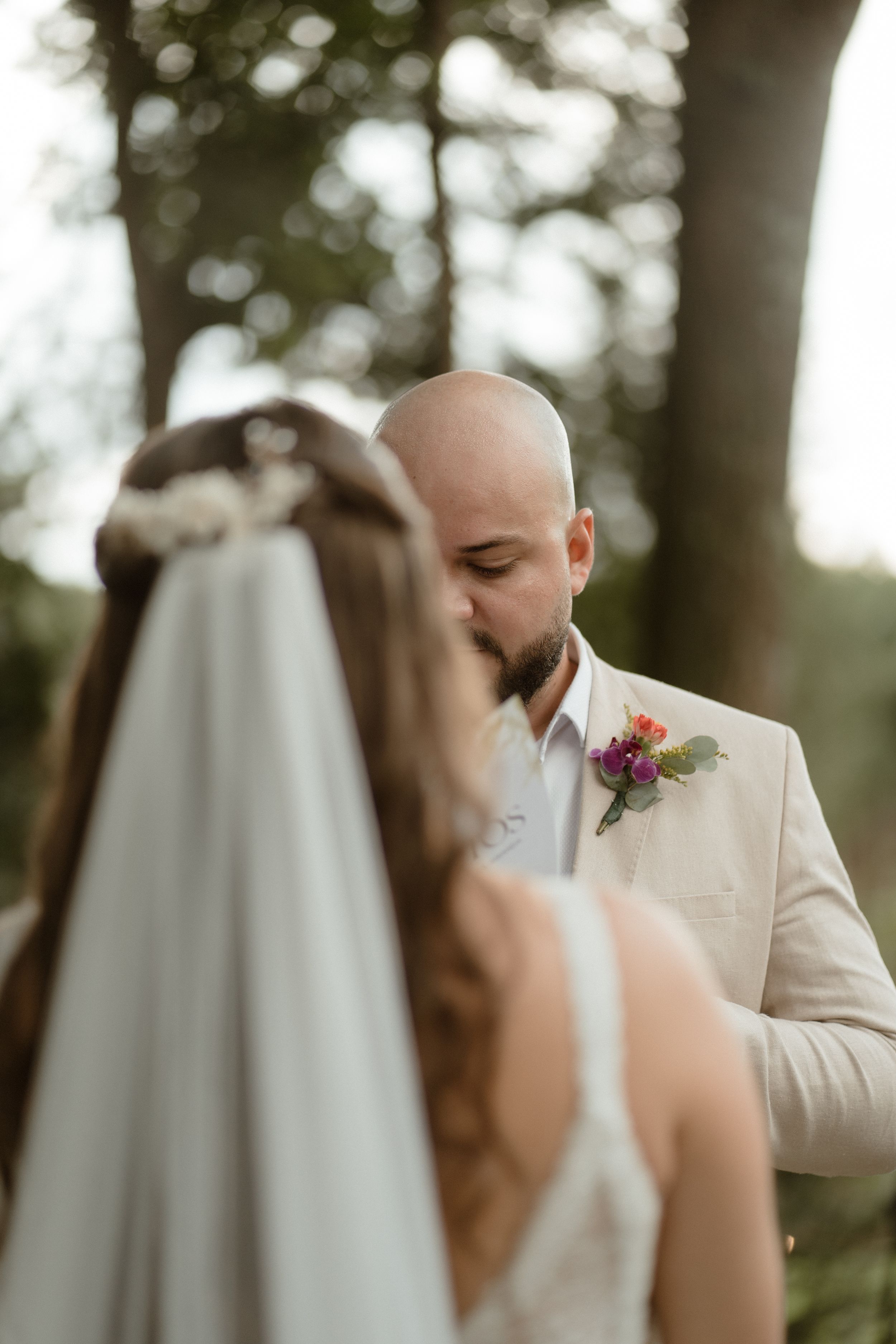 Intimate wedding moment captured in soft focus with natural outdoor lighting.