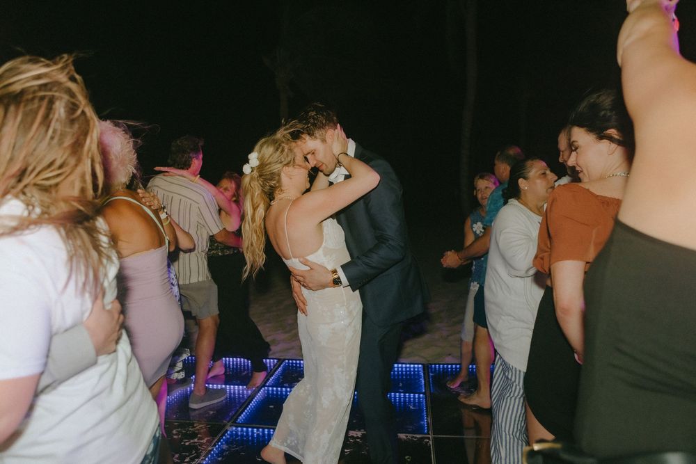 Couples dance together on an illuminated dance floor during an evening celebration.