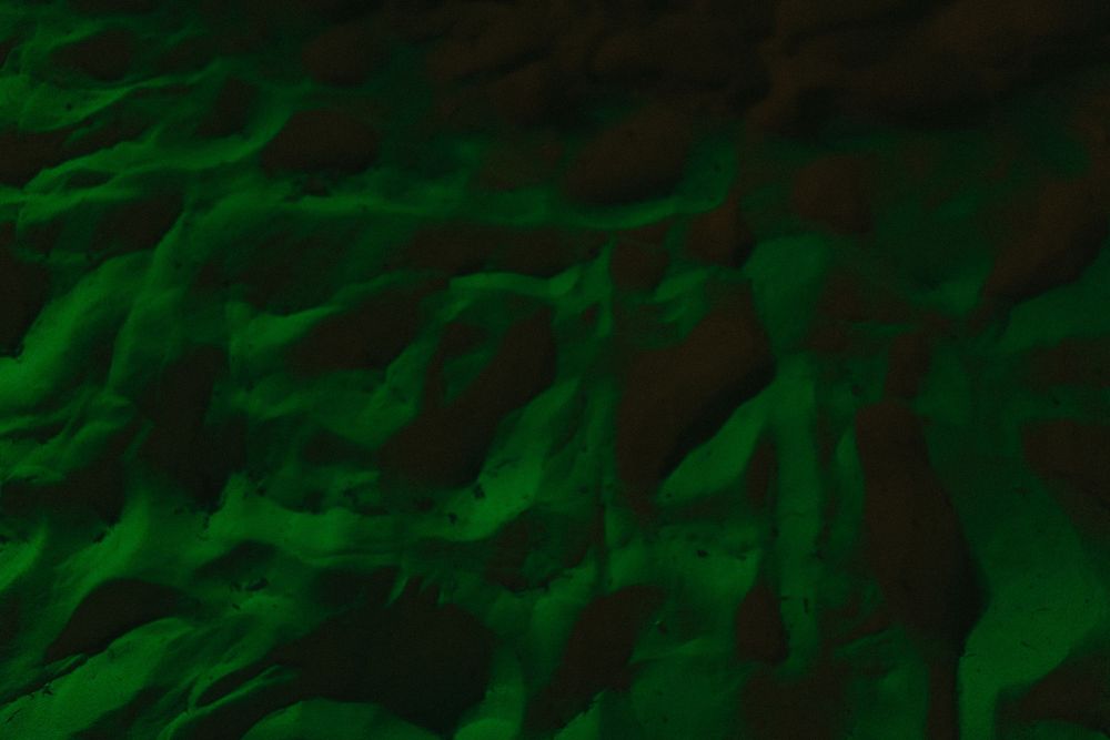 Abstract green waves and ripples create a dark textured background pattern.