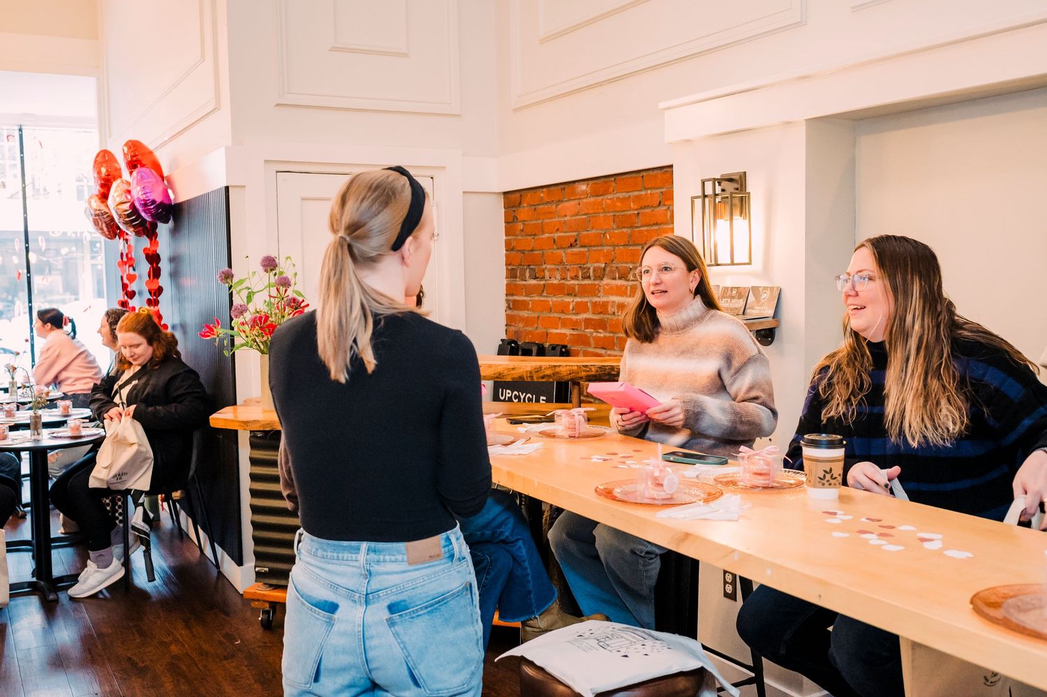 Several people enjoying a casual dining experience at a communal table in a bright restaurant setting.