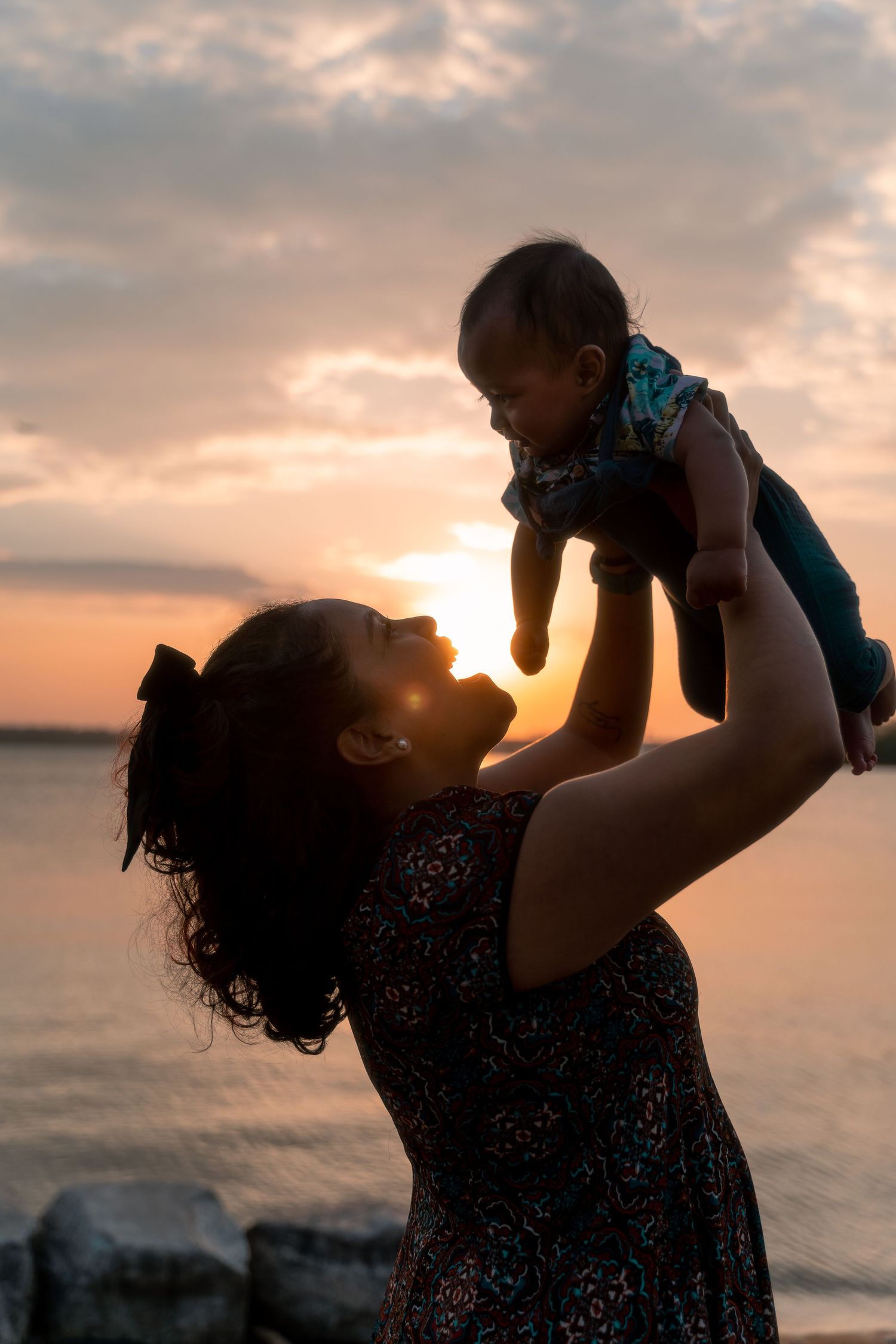 new mom holding her baby in golden hour lighting in national harbor maryland
