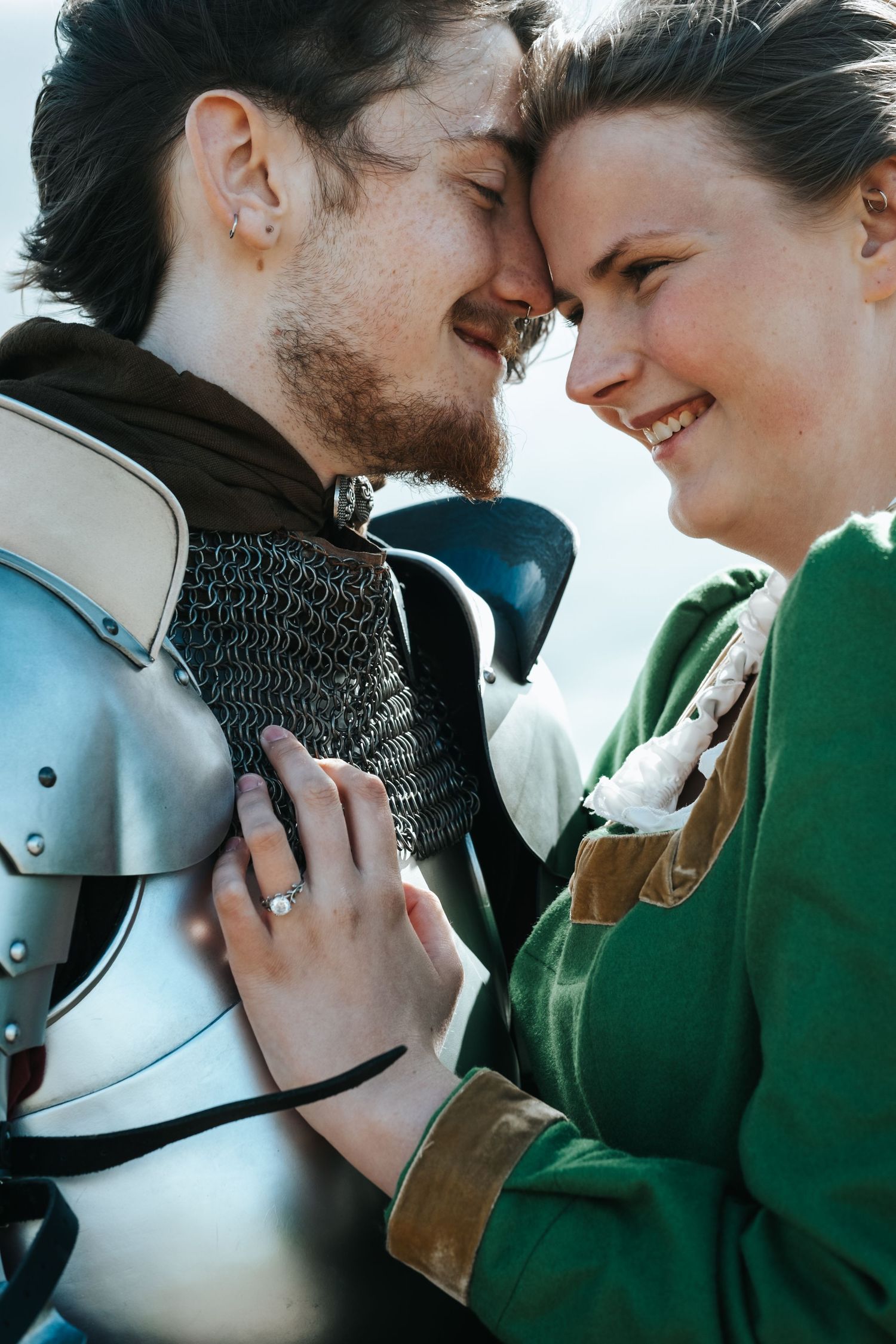 Romantic couple in medieval attire share an intimate moment with one wearing armor.