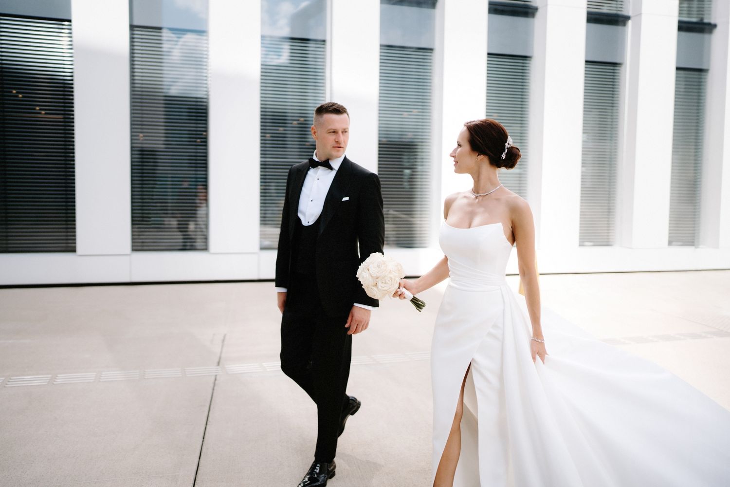A modern white interior hallway with dramatic columns creates an elegant wedding photography setting.