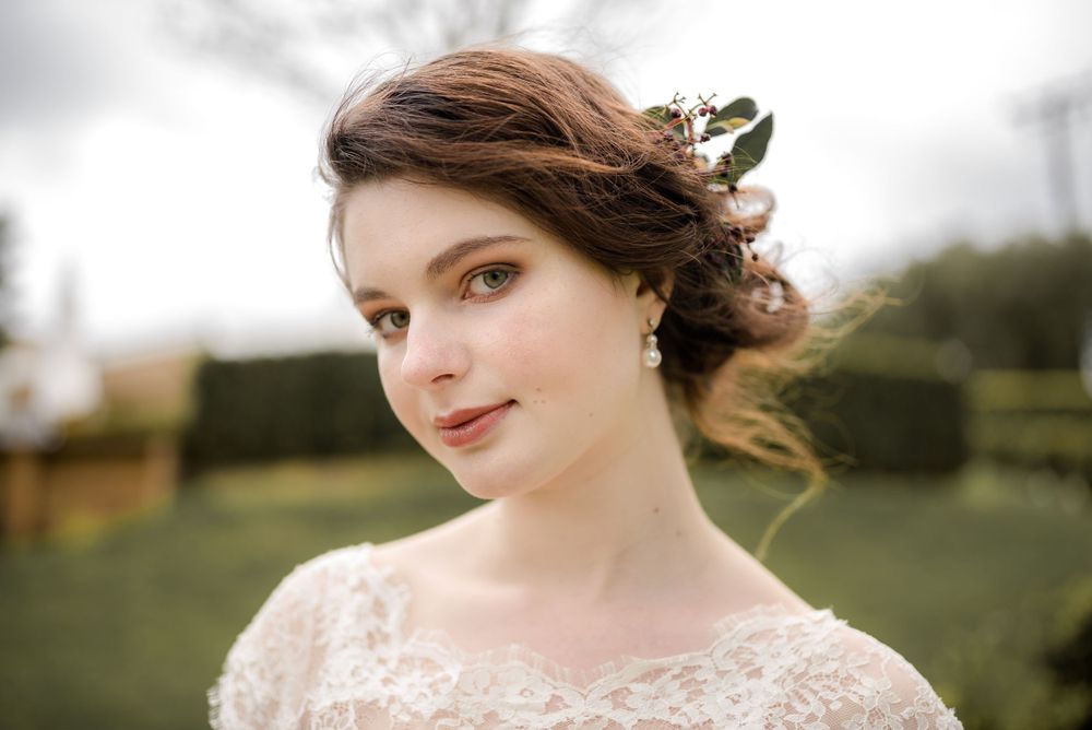 Elegant bridal portrait with vintage-inspired lace gown and romantic updo hairstyle.