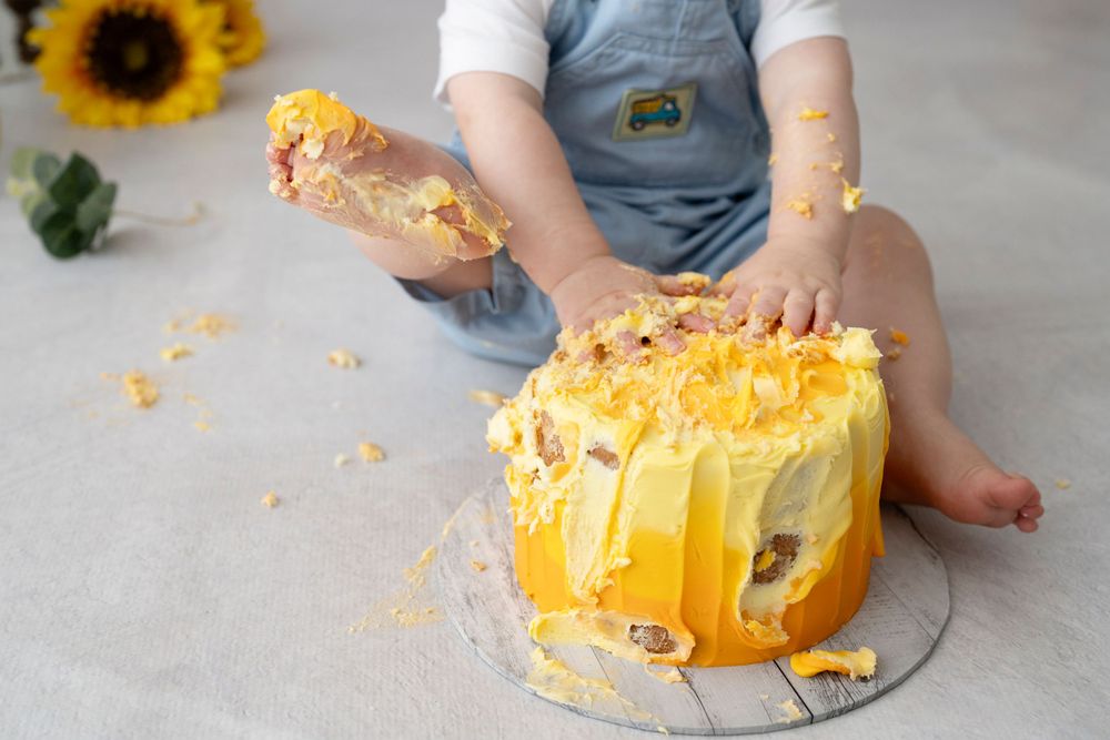 A messy birthday cake with a small child's foot covered in icing