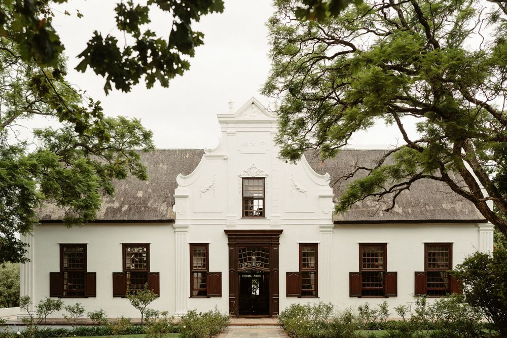 Classic white Cape Dutch style building with symmetrical windows and distinctive gable roof.