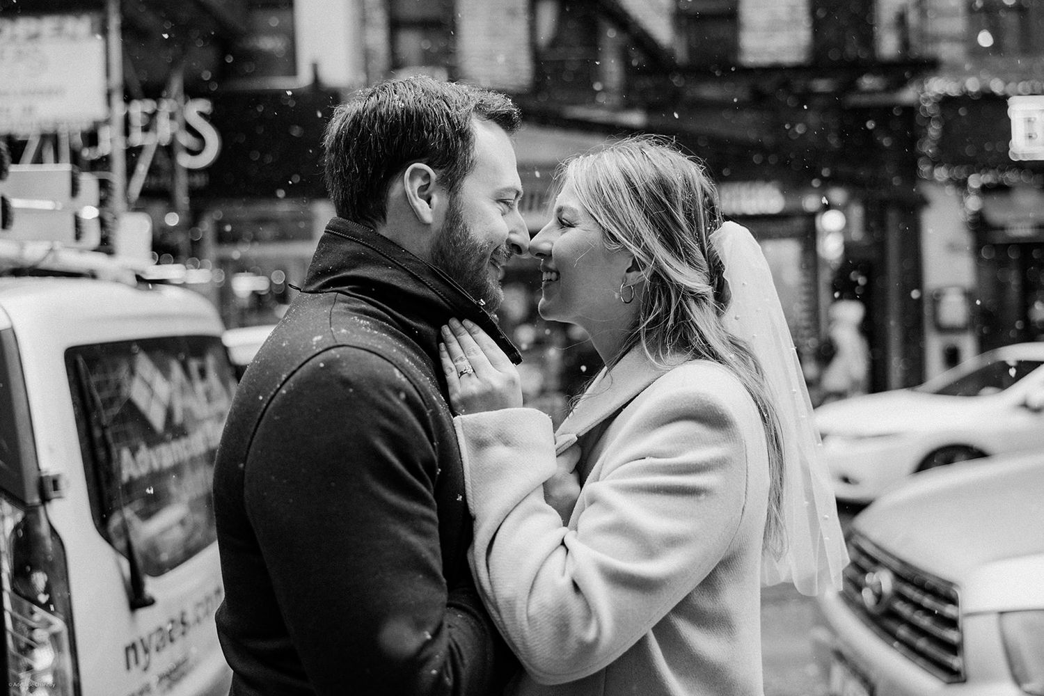 A black and white photo of a bride kissing her groom on a New York City street, capturing an elegant and heartfelt wedding moment in the cit