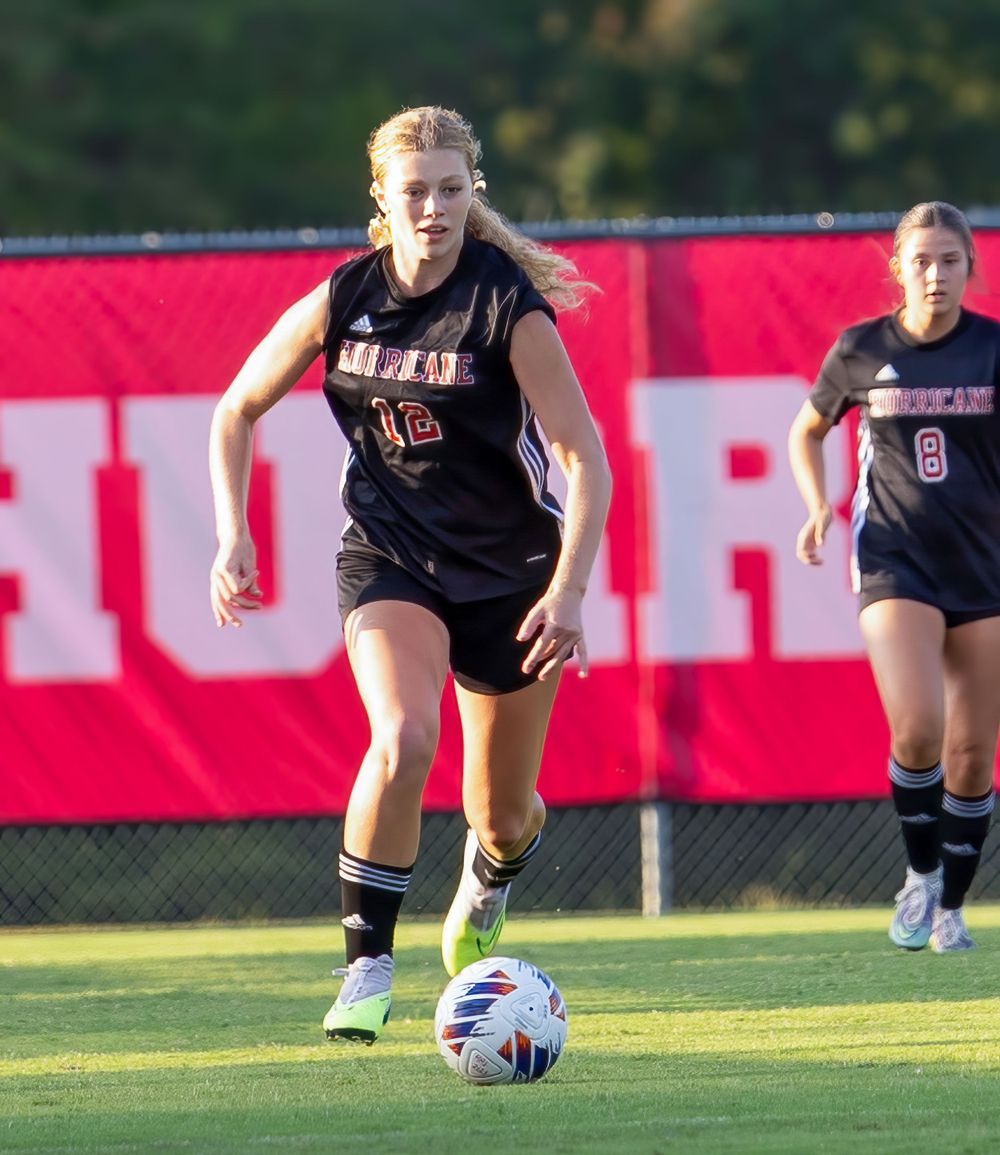 Soccer player controlling ball during match on field with red signage visible.
