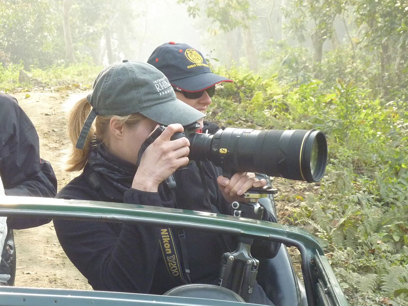 Kelly J. Russo using large telephoto lens mounted on a car window while photographing rhinos in India.