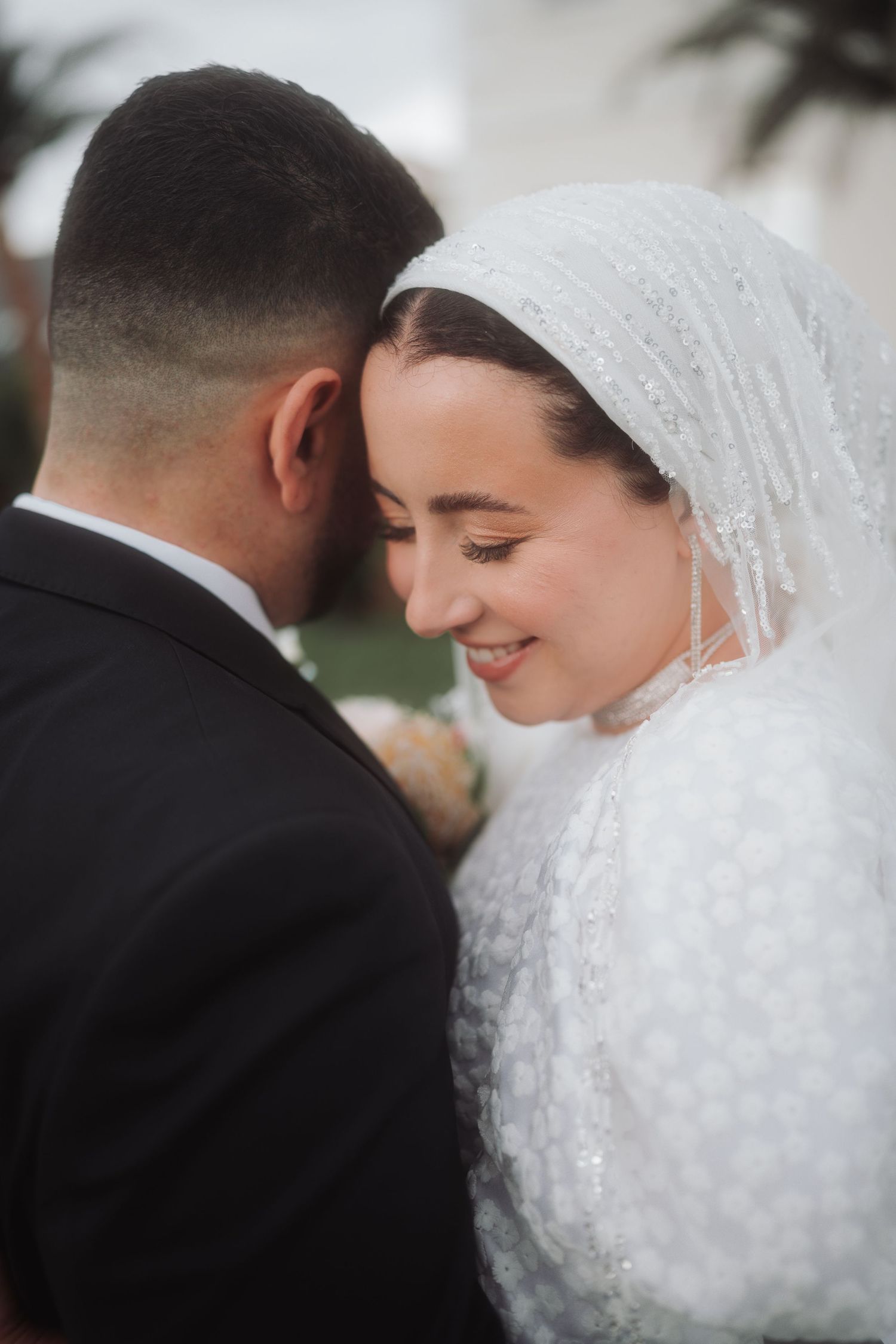 An intimate wedding portrait showing a tender moment between a couple in traditional wedding attire.