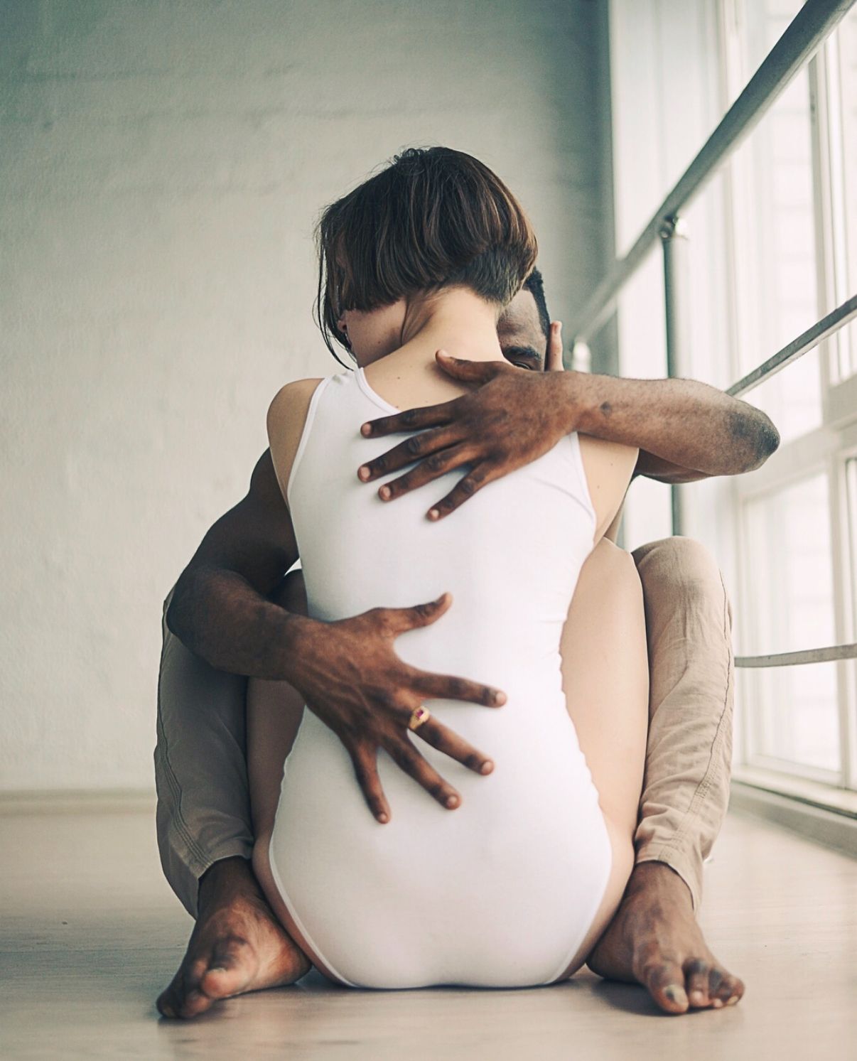 Artistic dance portrait showing intimate embrace against window light.