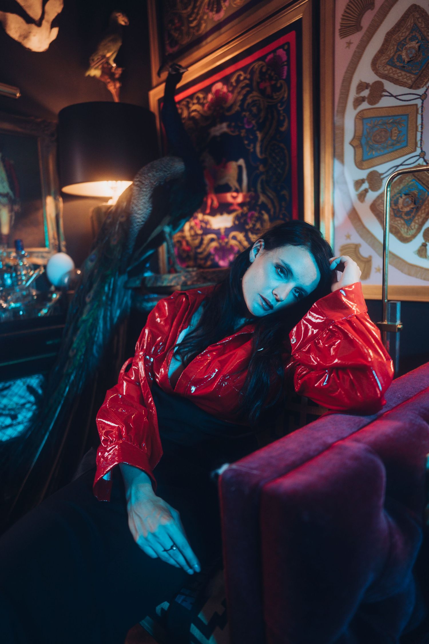 Moody portrait in red jacket against ornate vintage decor.