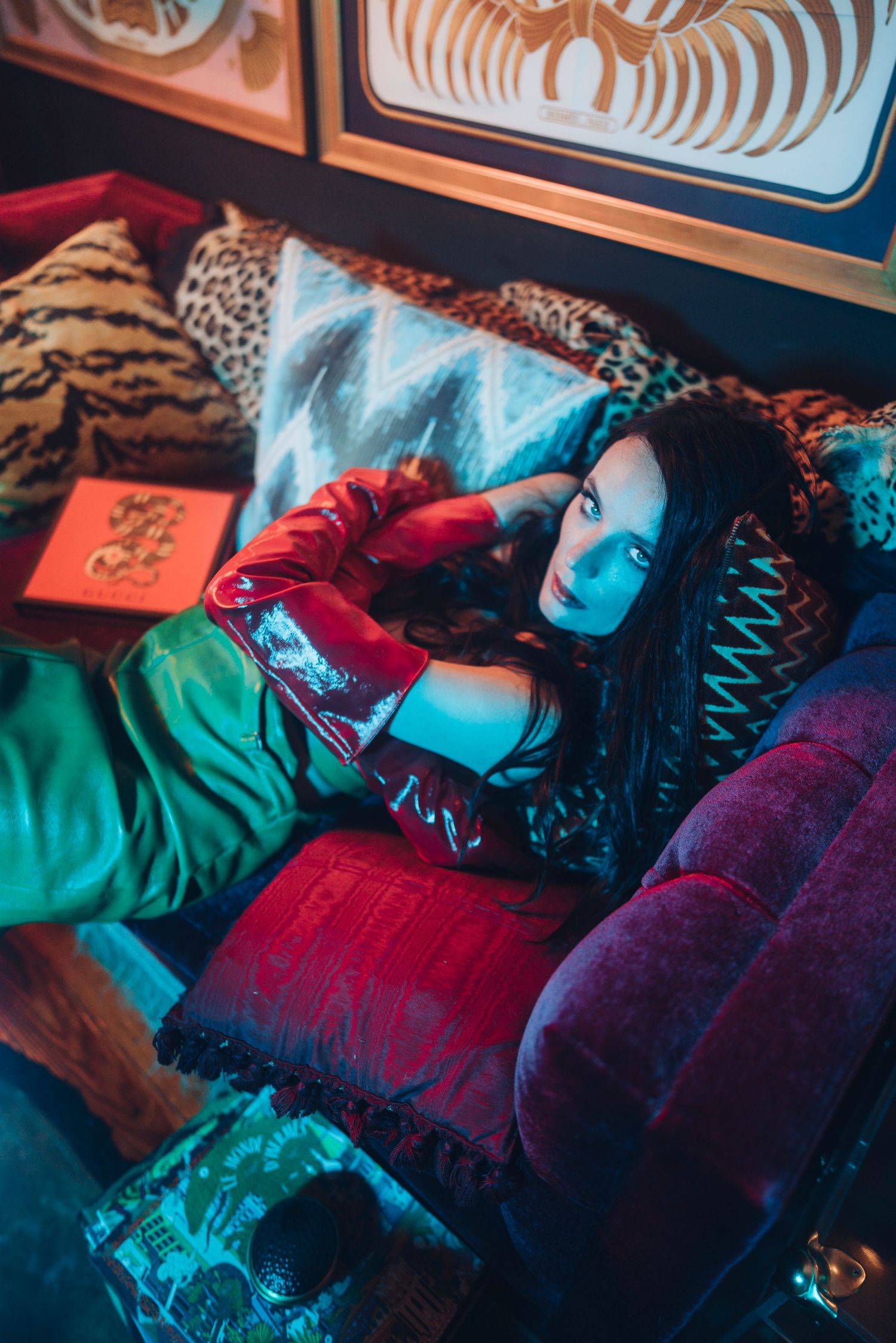 Moody editorial photo with dramatic red and blue lighting in vintage style interior setting.