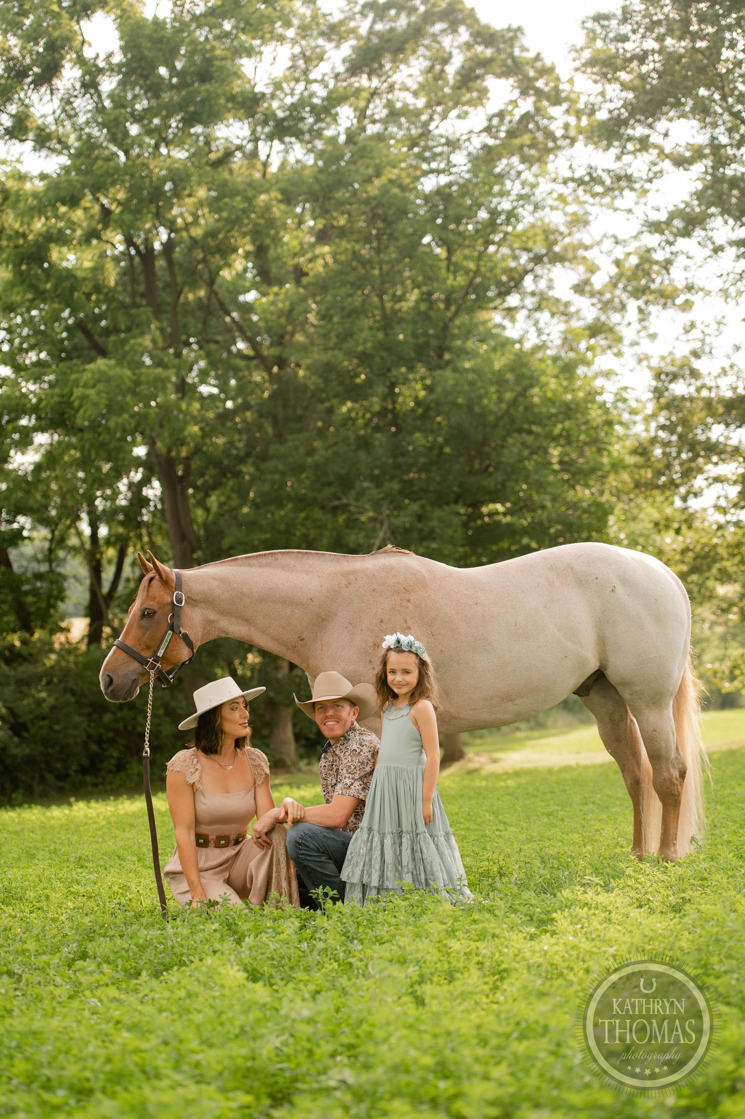 A countryside family portrait with a beautiful cream horse in a lush green setting.