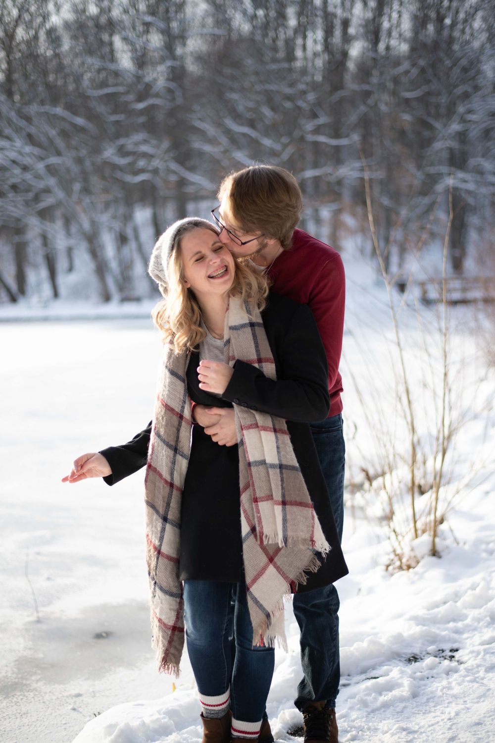 A romantic moment captured between a couple playing in the snow wearing winter attire.